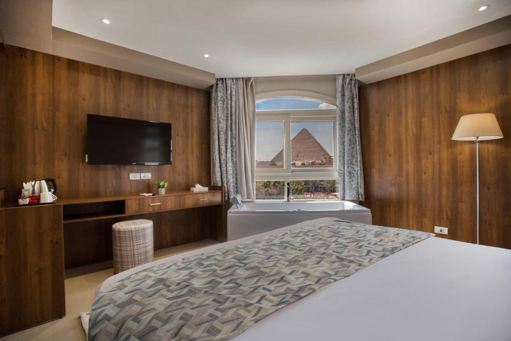 Schlafzimmer mit einem Bett, einem TV und einem Fenster in der Unterkunft NOZOL PYRAMIDS HOTEL in Kairo