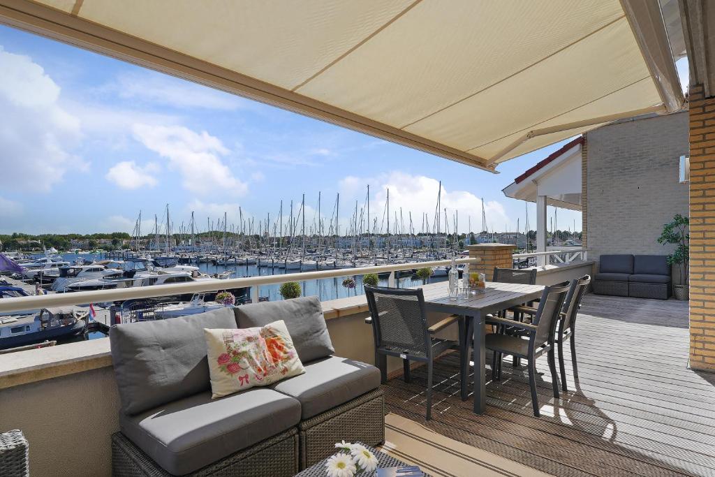 einen Balkon mit einem Tisch und Stühlen sowie einen Yachthafen in der Unterkunft Appartement in Zeeland - Kabbelaarsbank 512 - Port Marina Zélande - Ouddorp - With garage - not for companies in Ouddorp