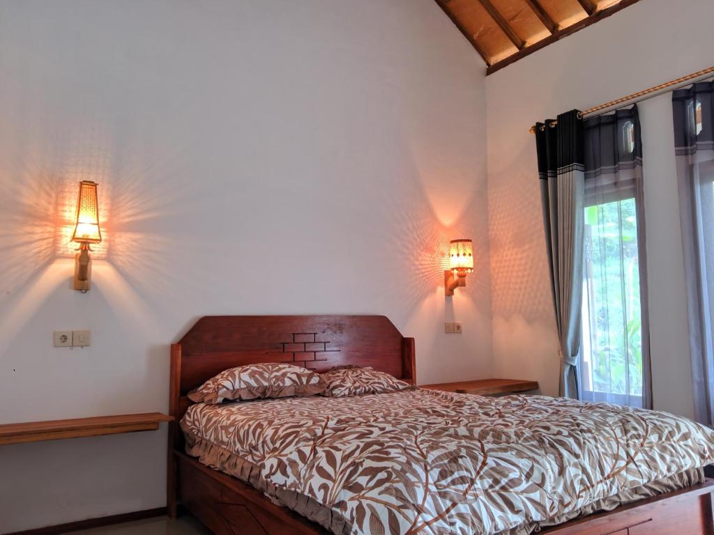 a bedroom with a bed with two lamps and a window at Sarang Walet Homestay in Tetebatu