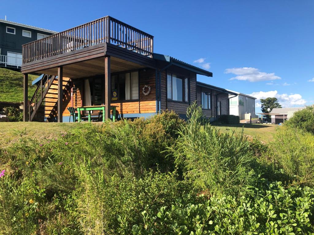 a house with a balcony on top of a field at Emma's Beach Cottage in Great Brak River