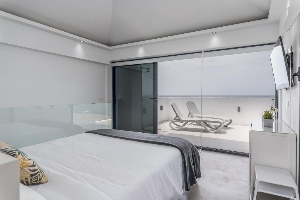 a bedroom with a bed and a glass wall at TORREÓN FRENTE AL MAR in Adeje