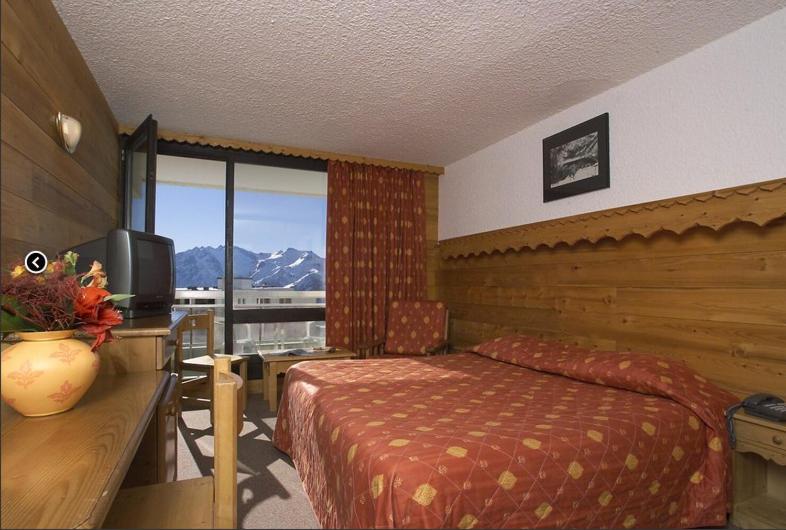 a bedroom with a bed and a desk with a television at Hôtel Le Dôme in L&#39;Alpe-d&#39;Huez