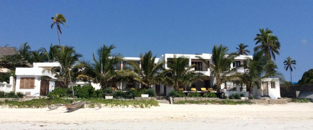 a white house on the beach with palm trees at La Villa de Victor Kigomani in Matemwe