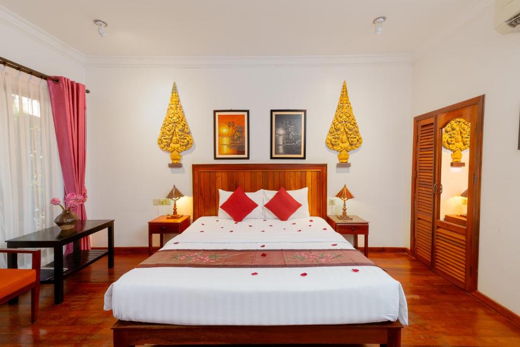 a bedroom with a large bed with red pillows at Asanak D'Angkor Boutique Hotel in Siem Reap
