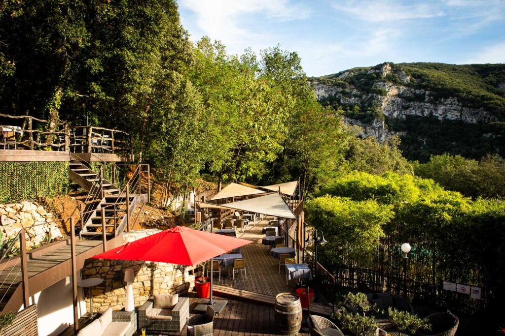 a patio with a red umbrella and tables and chairs at Le Belvedere in Vallon-Pont-dʼArc