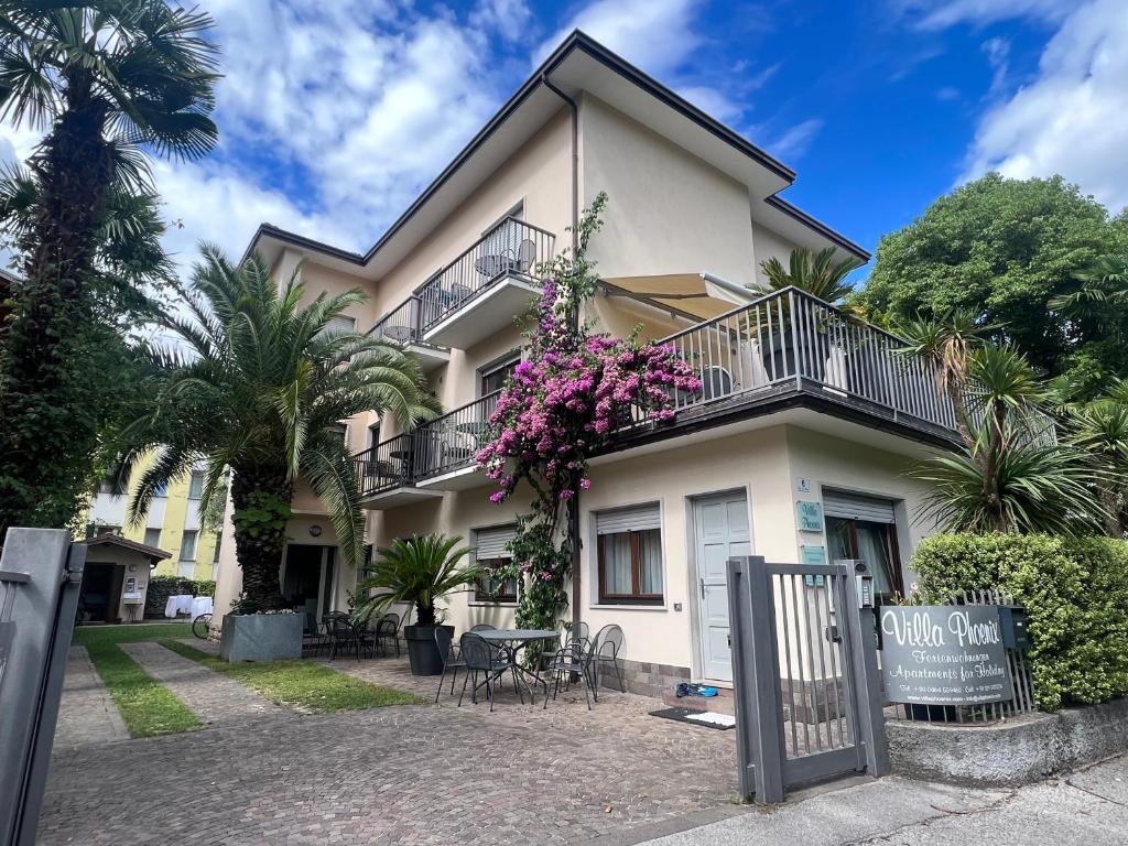 uma grande casa branca com flores roxas na varanda em Villa Phoenix - Lake Apartments em Riva del Garda