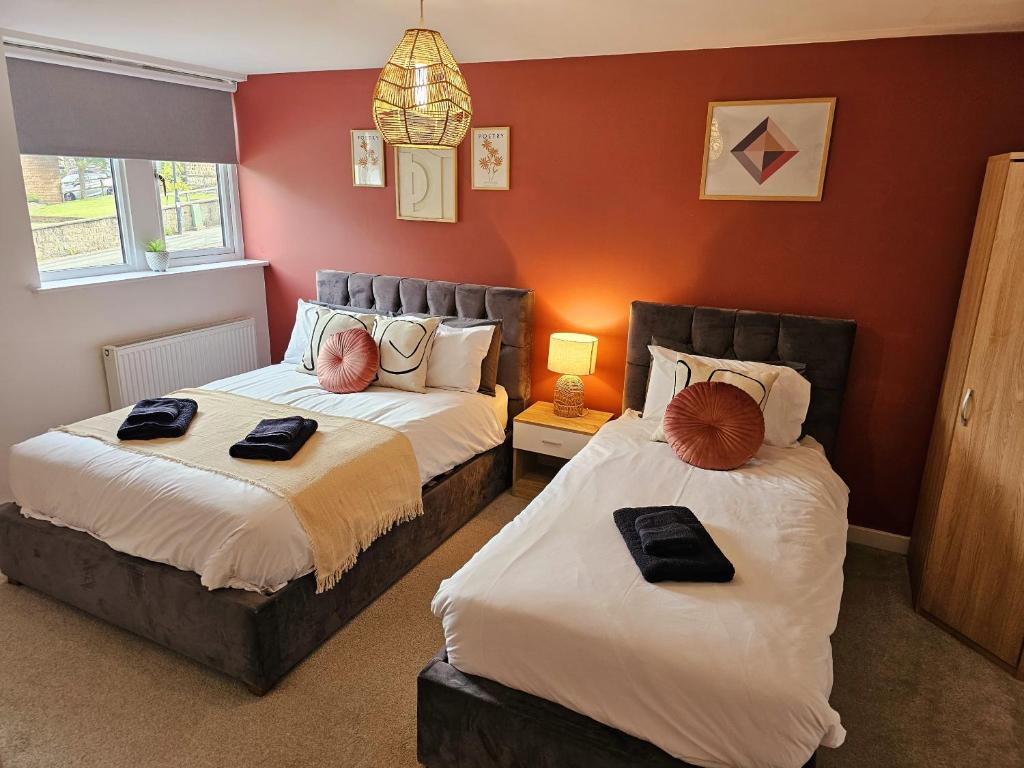 two beds in a room with red walls at Homebird Property - Epsom Apartment in Harrogate