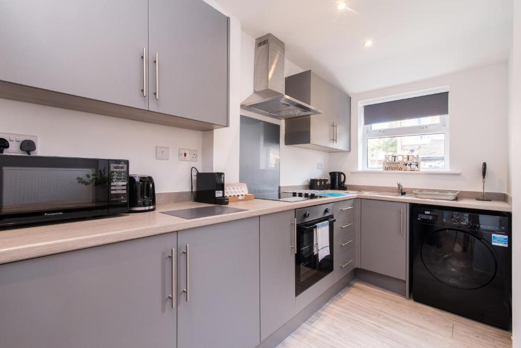 a kitchen with white cabinets and a washer and dryer at Thurgarton House - Cosy and Calm 2bed in Nottingham