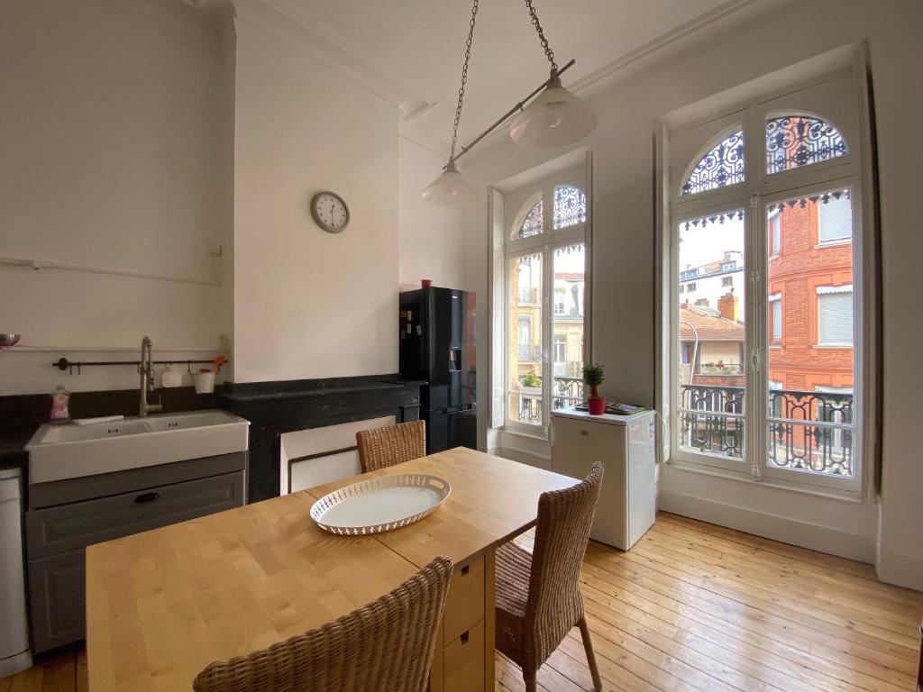 une cuisine avec une table et des chaises et une cuisine avec des fenêtres dans l'établissement L'Hypercentre - Au coeur de la vie Toulousaine, à Toulouse