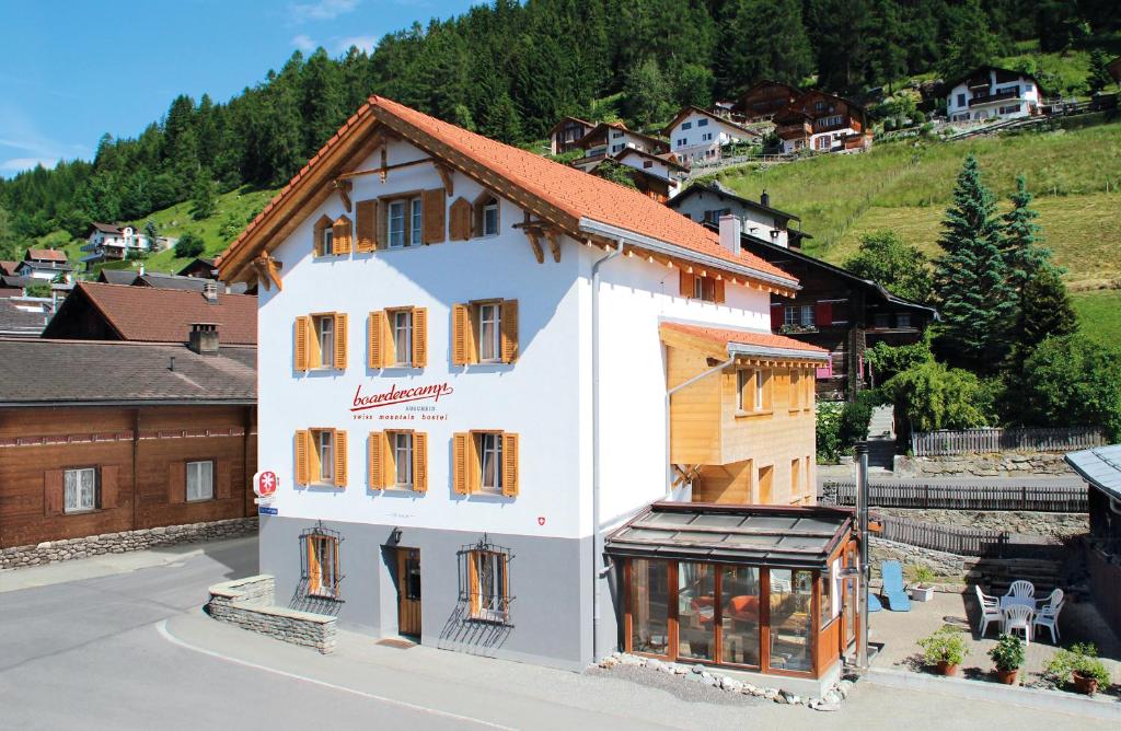 a large white building with windows on a street at Boardercamp Laax - swiss mountain hostel in Ruschein