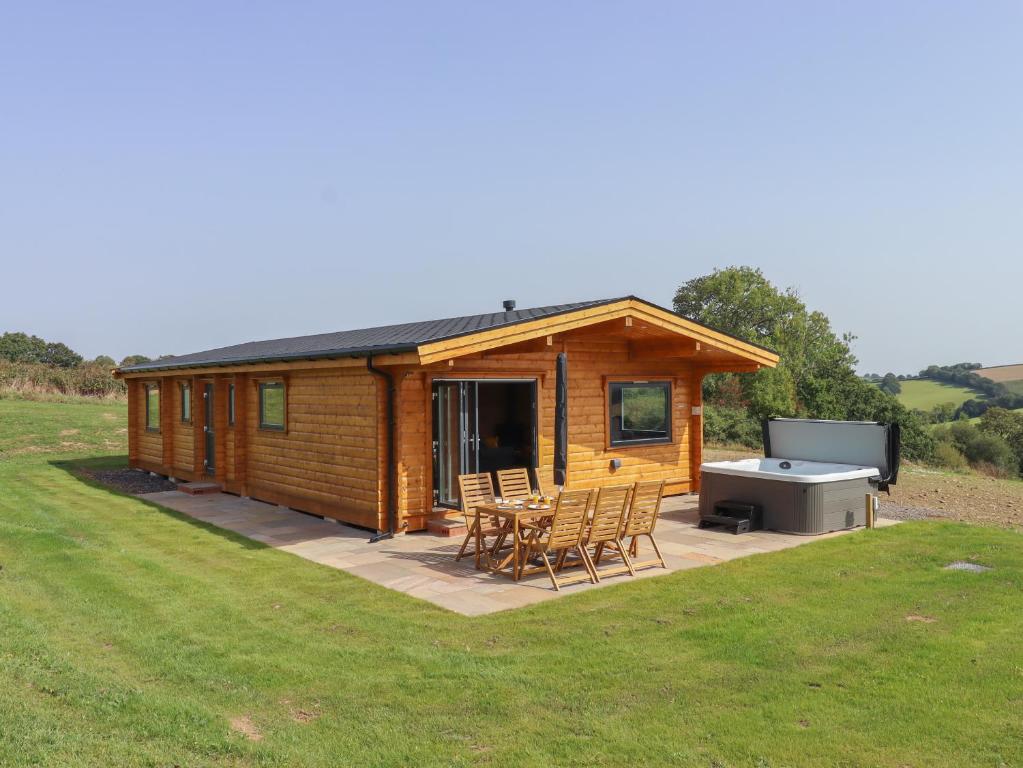 a log cabin with a picnic table and a grill at Bluebell Lodge in Exeter