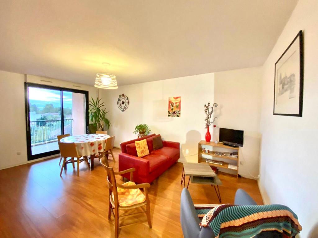 een woonkamer met een rode bank en een tafel bij La Garonne - T3 avec parking privé in Toulouse
