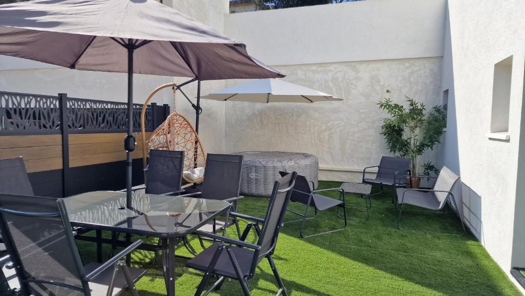 een patio met een tafel en stoelen en een parasol bij Cocooning LE MUGEL aux portes des calanques de Cassis & SPA in Carnoux