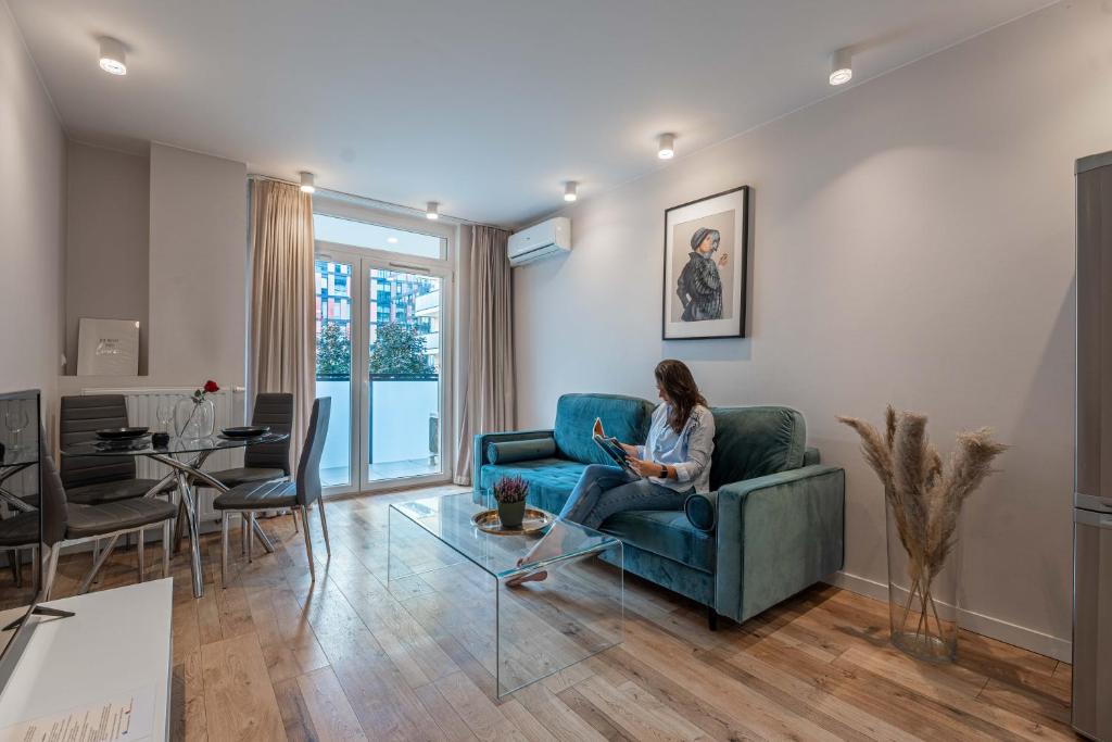 a woman sitting on a couch in a living room at Pure Rental Apartments in Wrocław