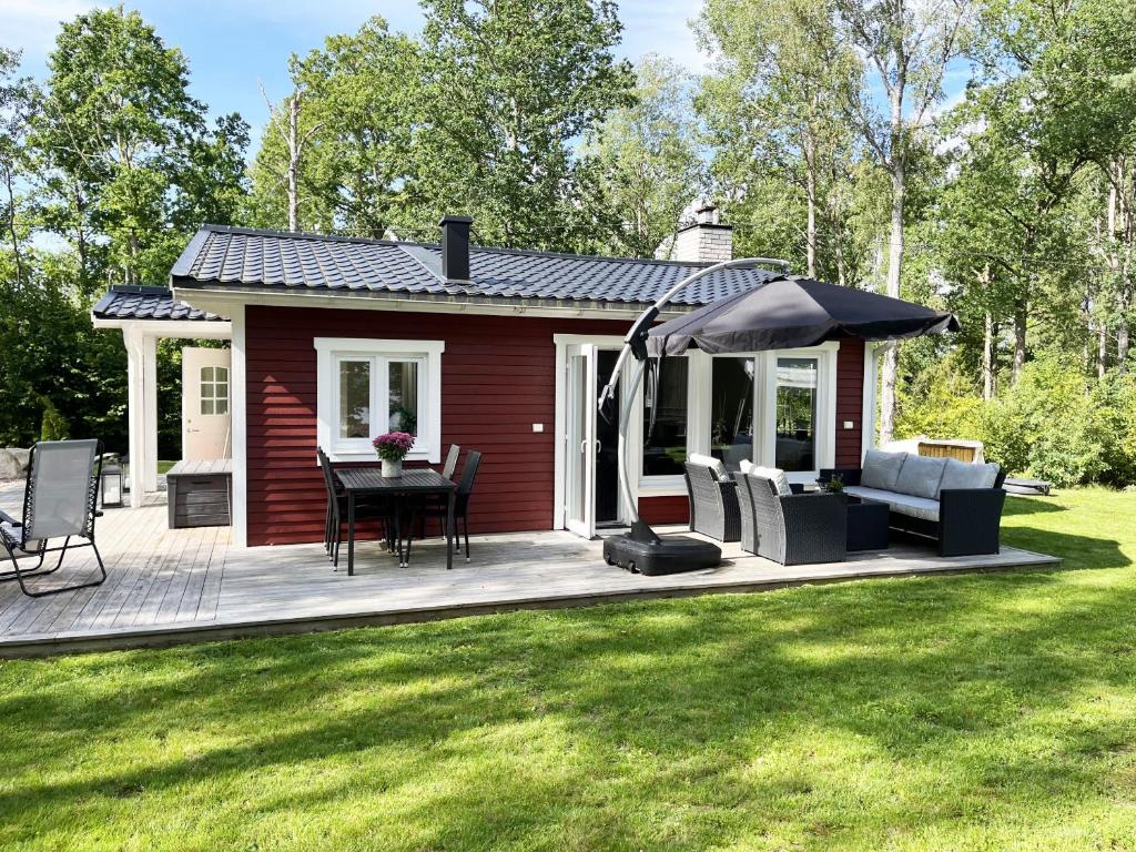 cabina roja con mesa, sillas y sombrilla en Nice, renovated red cottage located next to Lake Flaten, en Järnforsen