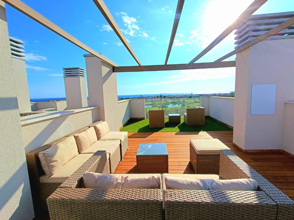 ein Wohnzimmer mit Sofas und Tischen auf dem Balkon in der Unterkunft Nuevo Ático Toyo. Vistas al mar, terraza, solarium, piscina, A/A, WiFi y Garaje in El Toyo