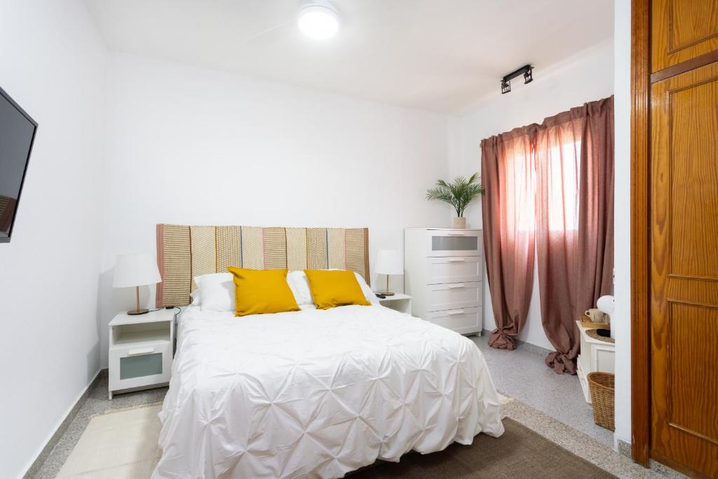 1 dormitorio blanco con 1 cama grande con almohadas amarillas en EDEN RENTALS 105 Surfy Stylish Bed&Coffee Room, en Granadilla de Abona