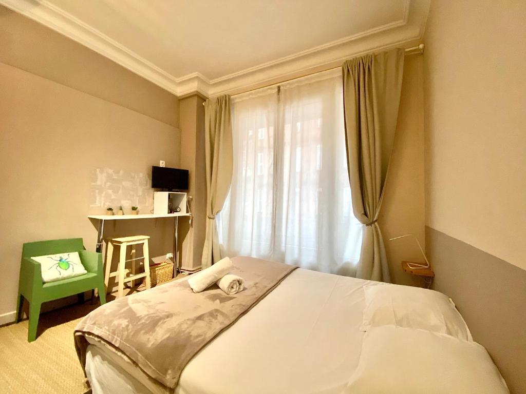 a bedroom with a bed and a window with a green chair at Les Capitole I - Studio avec climatisation in Toulouse