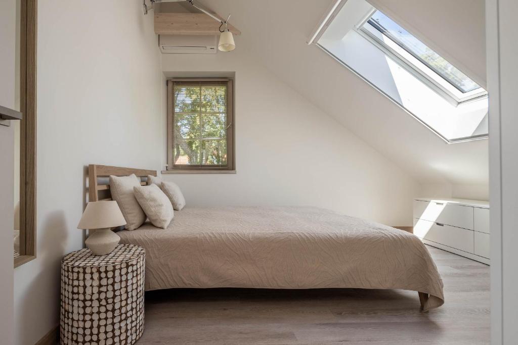a white bedroom with a bed and a window at Nauji apartamentai! Pamario 14 in Nida