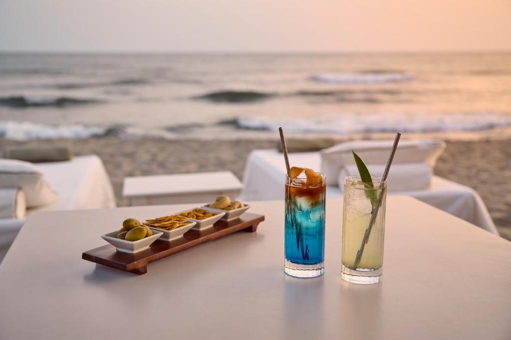 a table with a drink and a tray of food on the beach at Grand Hotel Imperiale in Forte dei Marmi
