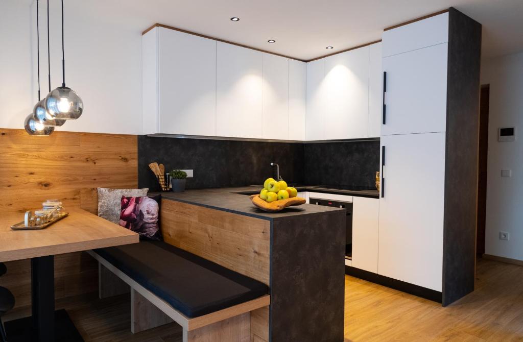 uma cozinha com armários brancos e uma mesa com uma taça de fruta em Appartement Sonnlicht em Falzes