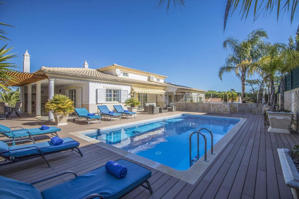 a swimming pool with blue lounge chairs and a house at Villa Joy in Olhos de Água