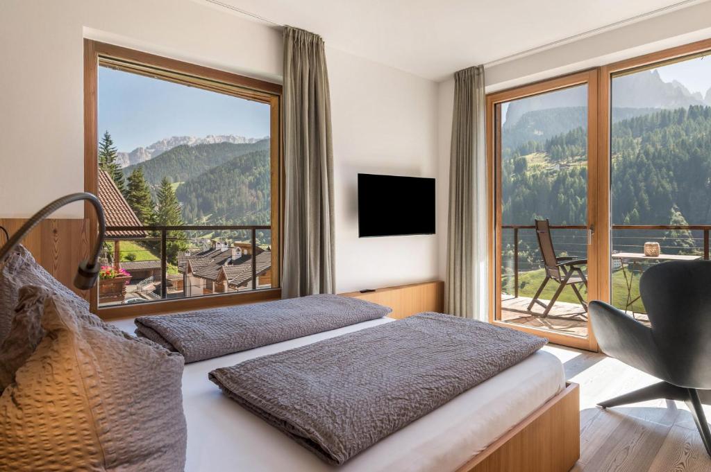 um quarto de hotel com duas camas e uma grande janela em Vista Dolomites Apartment Liberty em Santa Cristina in Val Gardena