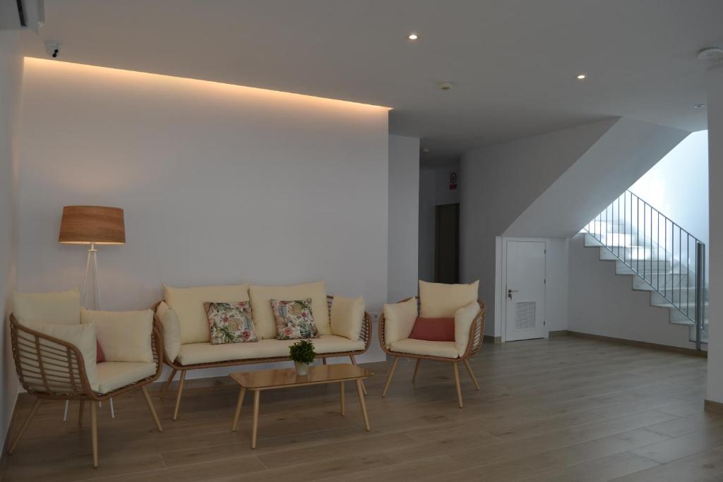 sala de estar con sofá y sillas y escalera en Hotel OASIS CENTRO, en Conil de la Frontera