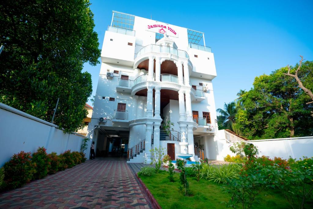 un edificio blanco con una pasarela de ladrillo rojo delante de él en JAMUNA VILLA, en Jaffna