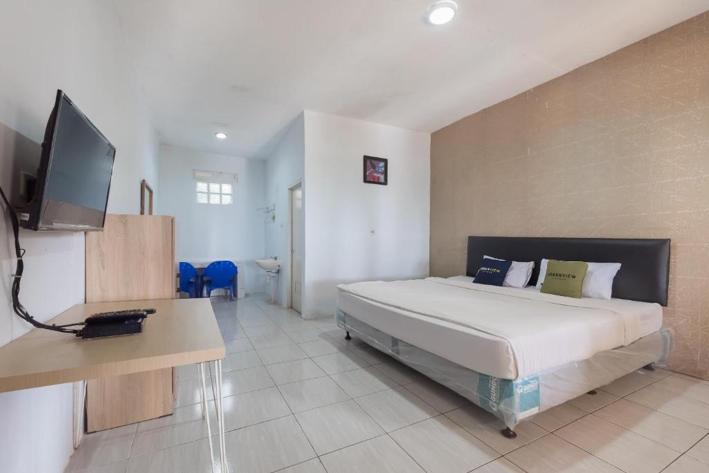 a bedroom with a bed and a desk and a television at Urbanview Hotel D'Pineapple Villa Ciater by RedDoorz in Subang
