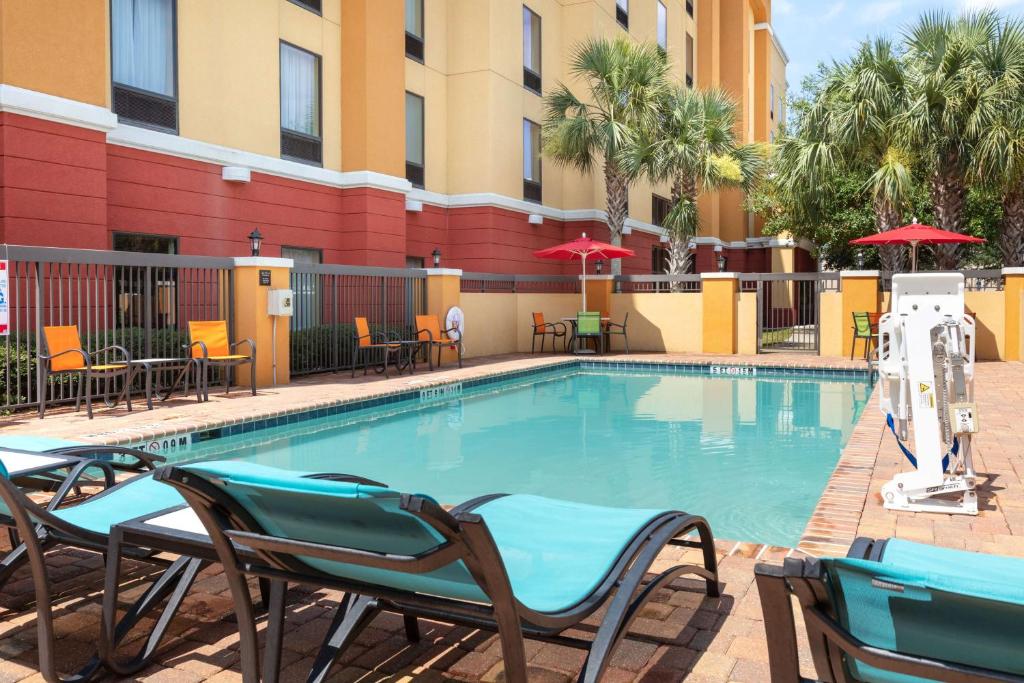 a swimming pool with chairs and tables in a hotel at Hampton Inn & Suites Jacksonville South - Bartram Park in Jacksonville