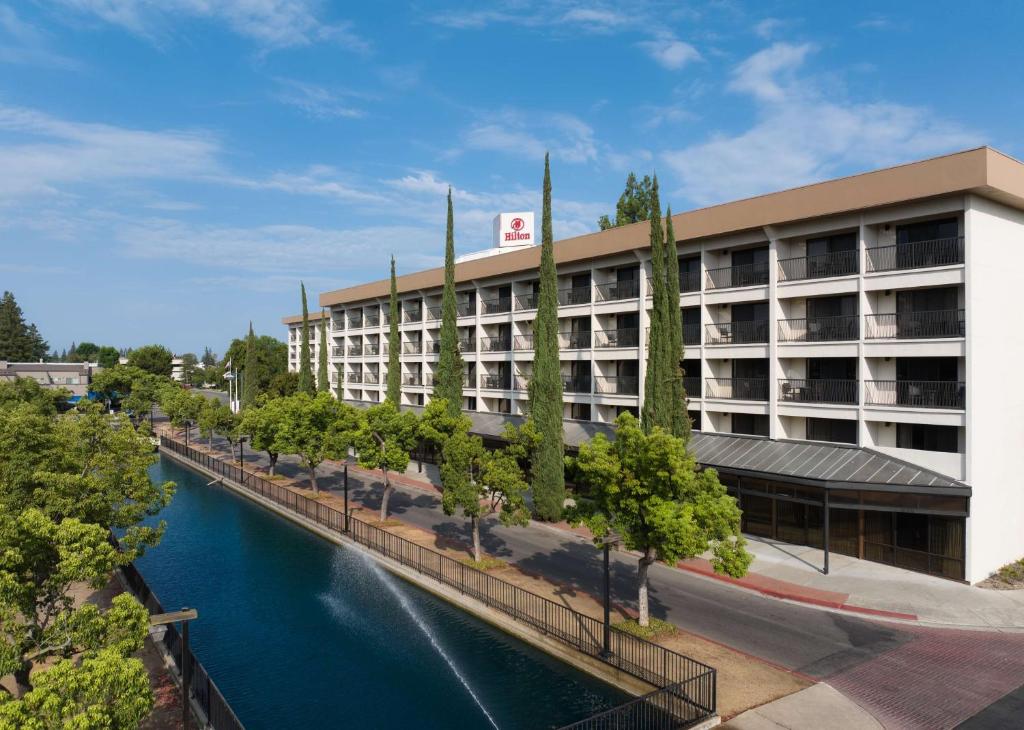 a hotel with a river in front of a building at Hilton Stockton in Stockton