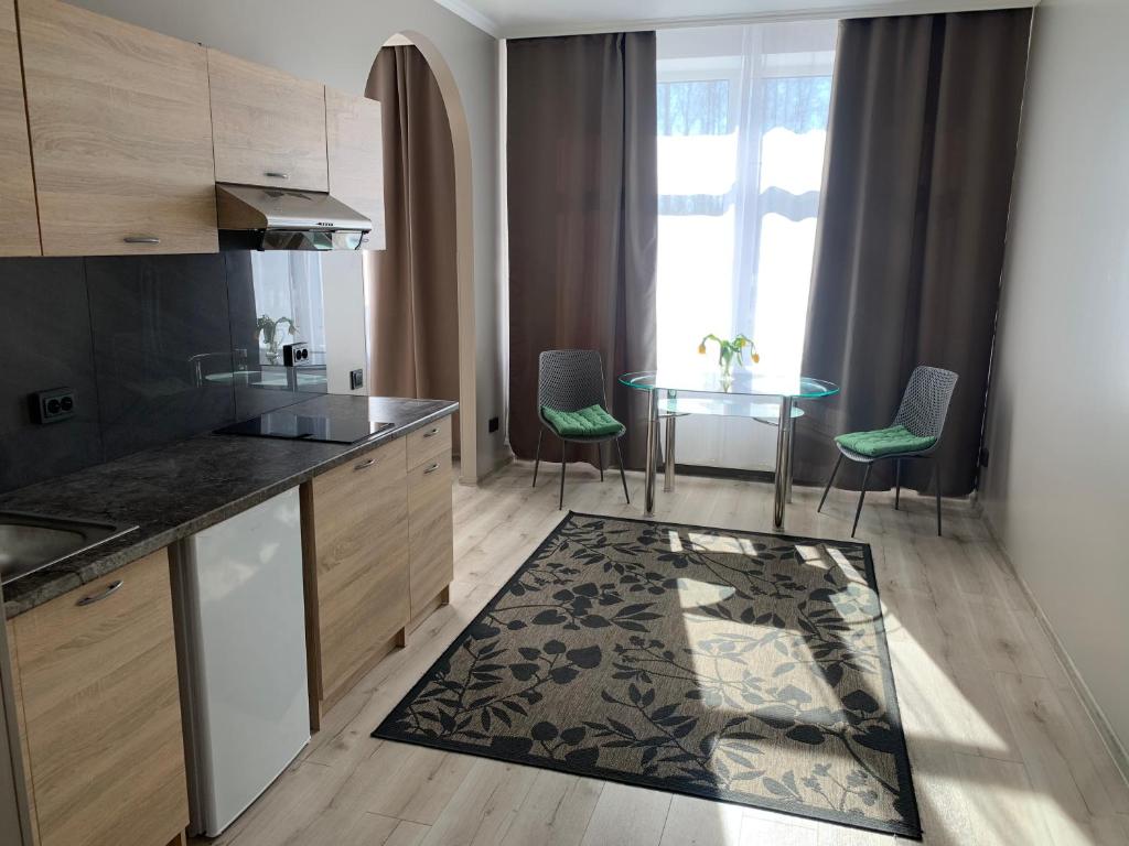 a kitchen with a table and chairs and a table with a rug at VILLA ROZA Guest House in Rēzekne