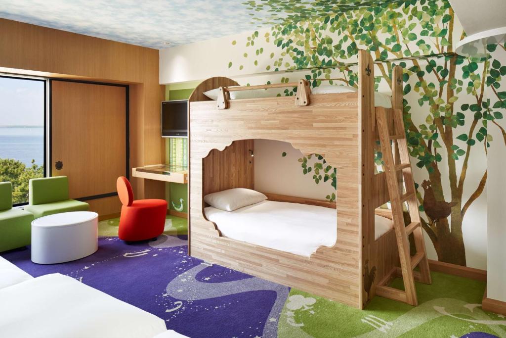 Cette chambre pour enfants est dotée de lits superposés et d'une fresque murale représentant les arbres. dans l'établissement Hilton Tokyo Bay, à Urayasu