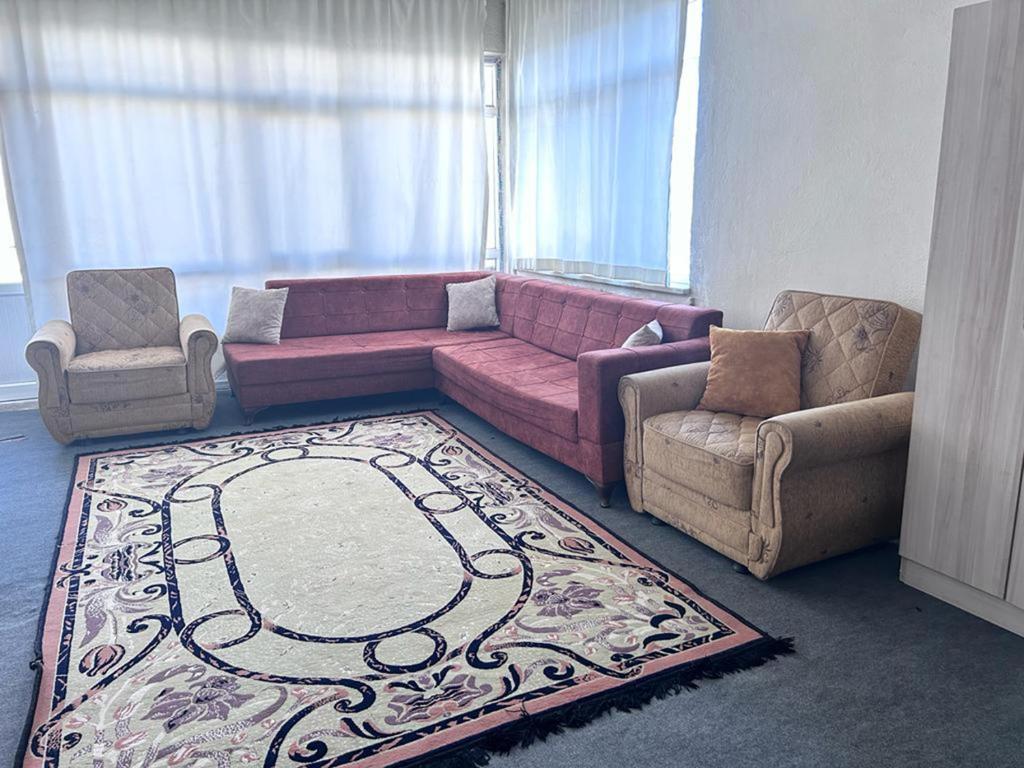 a living room with a pink couch and two chairs at CAN REZİDANS in Konya