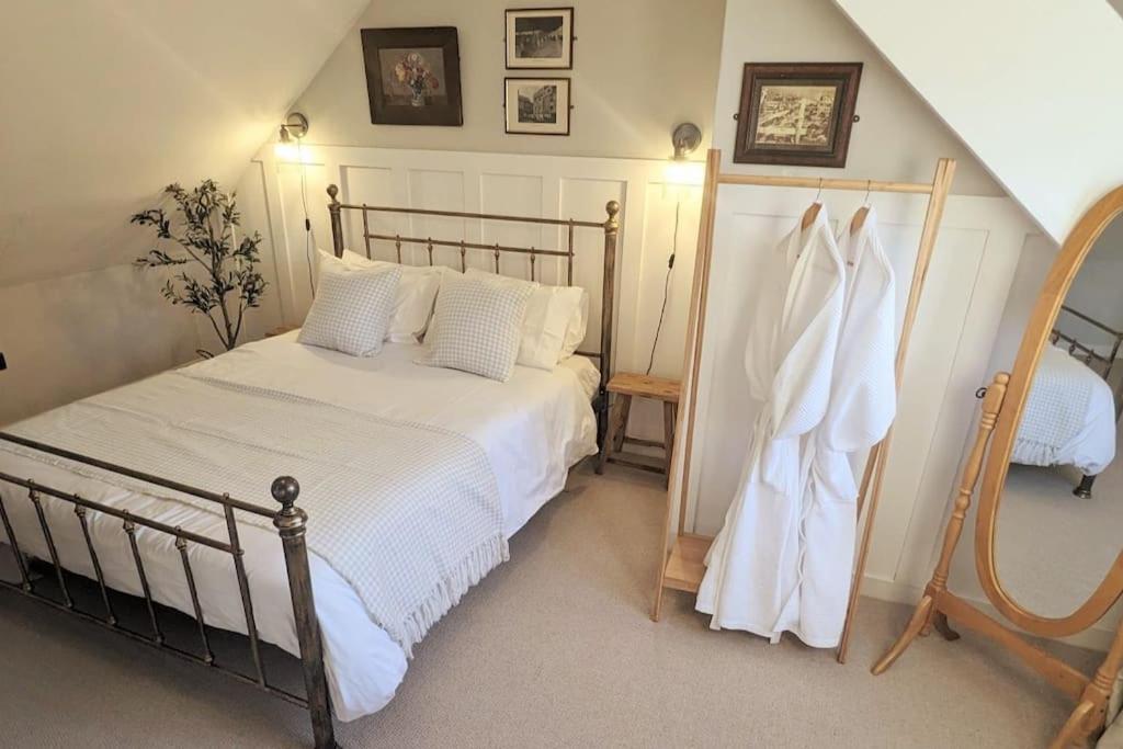 a bedroom with a bed with white sheets and a mirror at The Cottage @ 59 in Colmonell