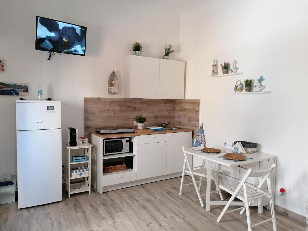 a kitchen with a white refrigerator and a table at Blue Cottage monolocale centro Sciacca in Sciacca