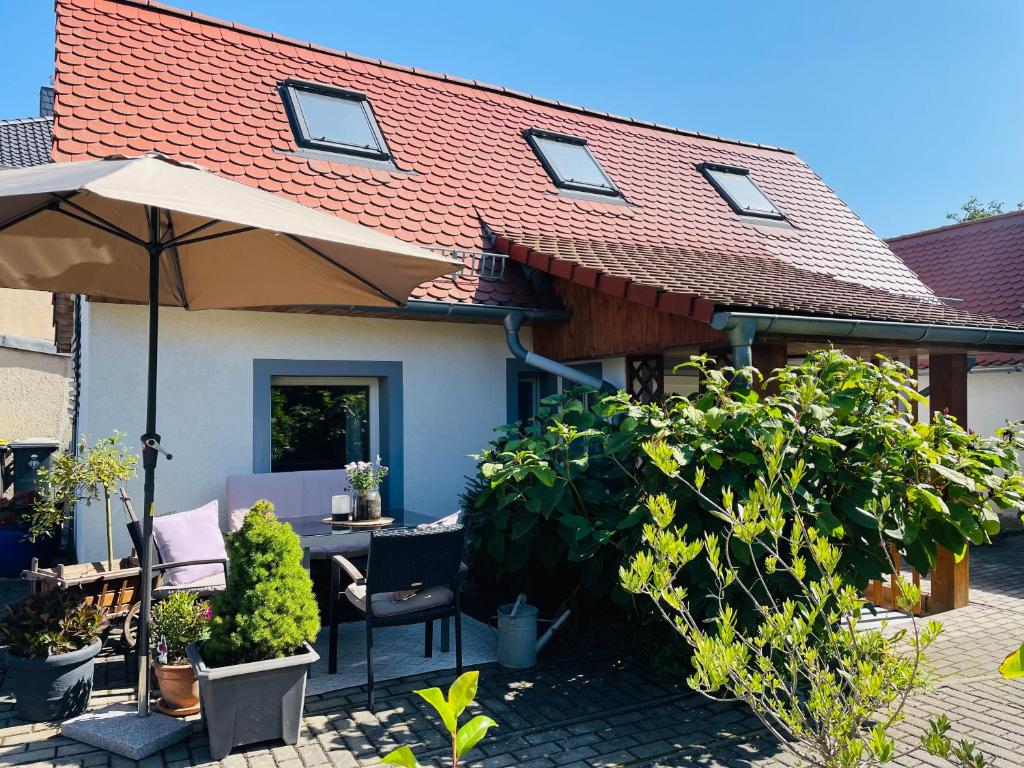 a house with an umbrella and a table and chairs at Ferienhaus Neuseenland in Großzössen