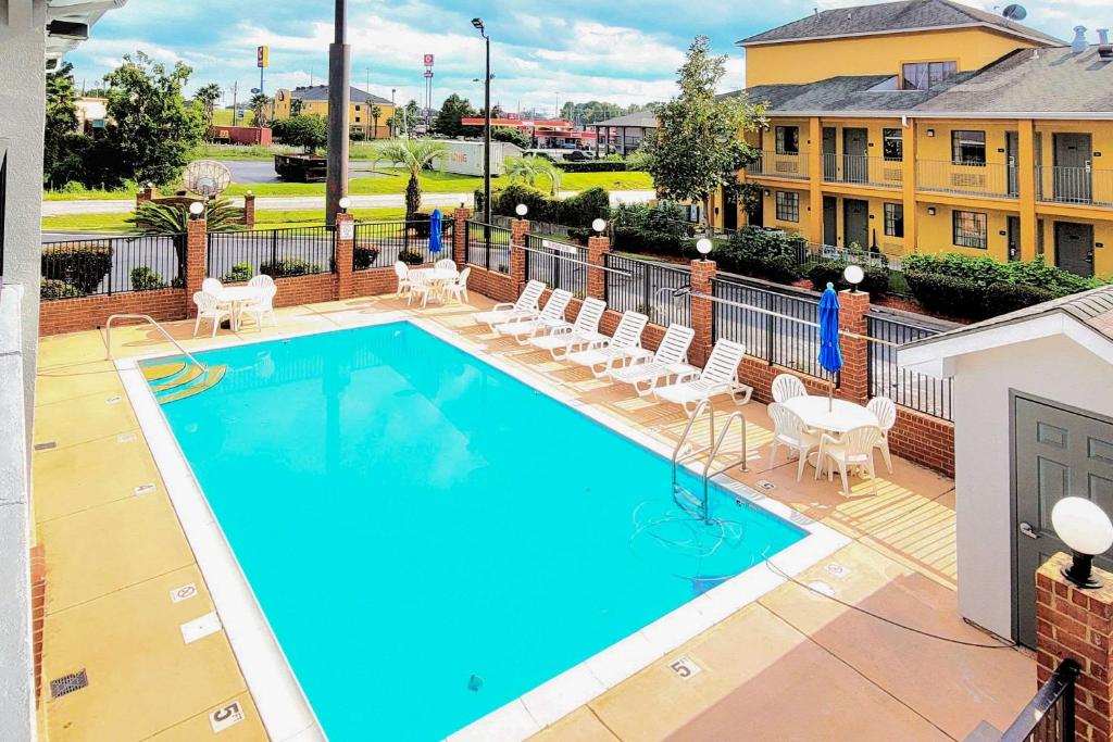 a swimming pool with chairs and a table and a building at Quality Inn Port Wentworth Savannah North in Port Wentworth