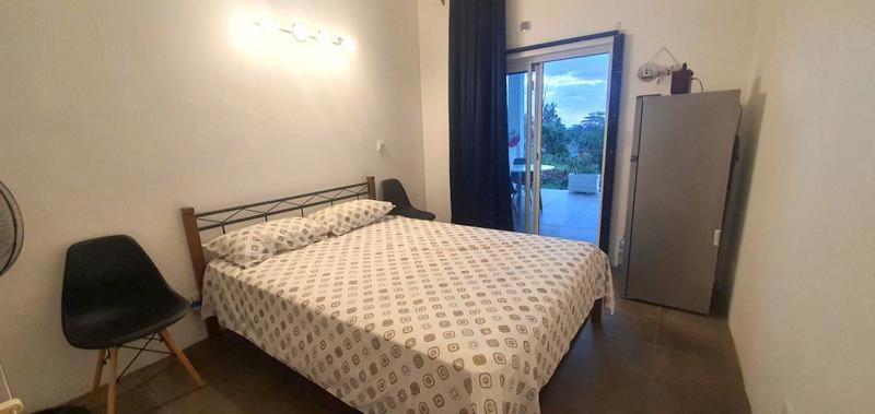 a bedroom with a bed and a chair and a window at El-Sangha Studio 2mina pieds de la plage de baie du cap in Baie du Cap