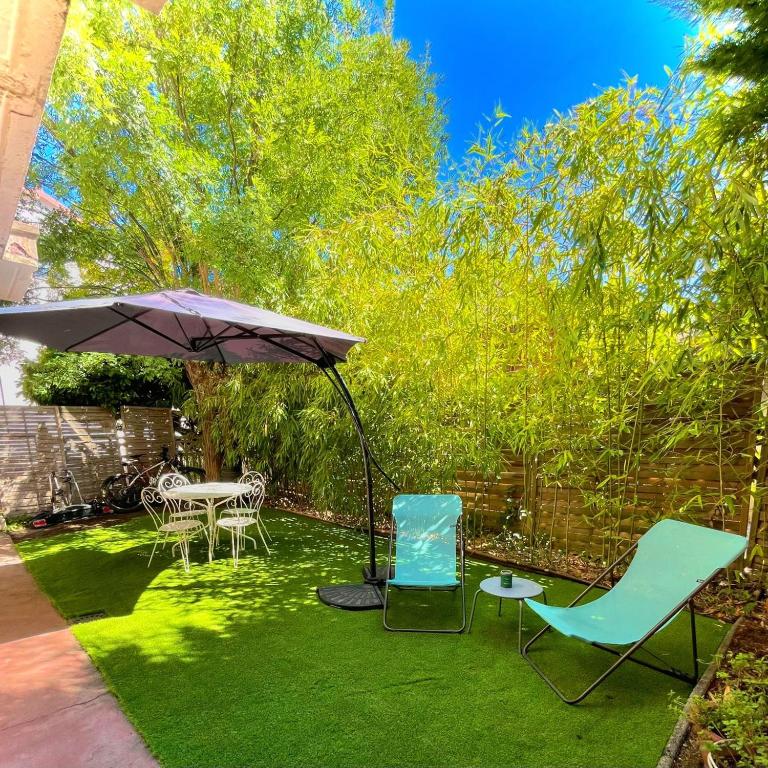 un patio avec deux chaises et un parasol dans l'établissement Les Bambous - Rez de jardin Millau Centre - Parking privatif, wifi, à Millau