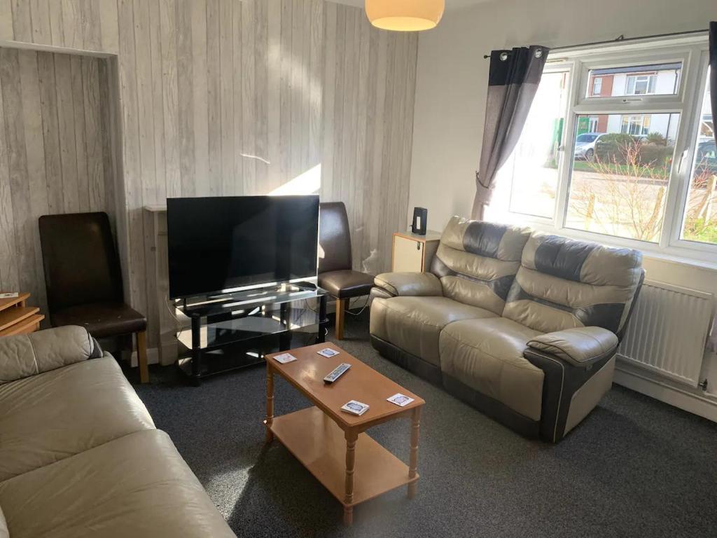 a living room with a couch and a flat screen tv at Ratcliffe House - Spacious 3 bedroom House in Sileby in Sileby