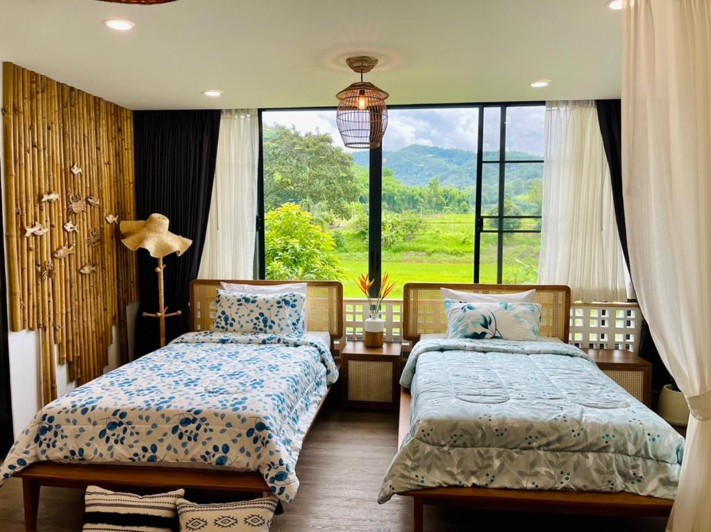 a bedroom with two beds and a large window at Pupah Kanna Pua-ปู๋ ป๋าล์ คันนา ปัว in Pua