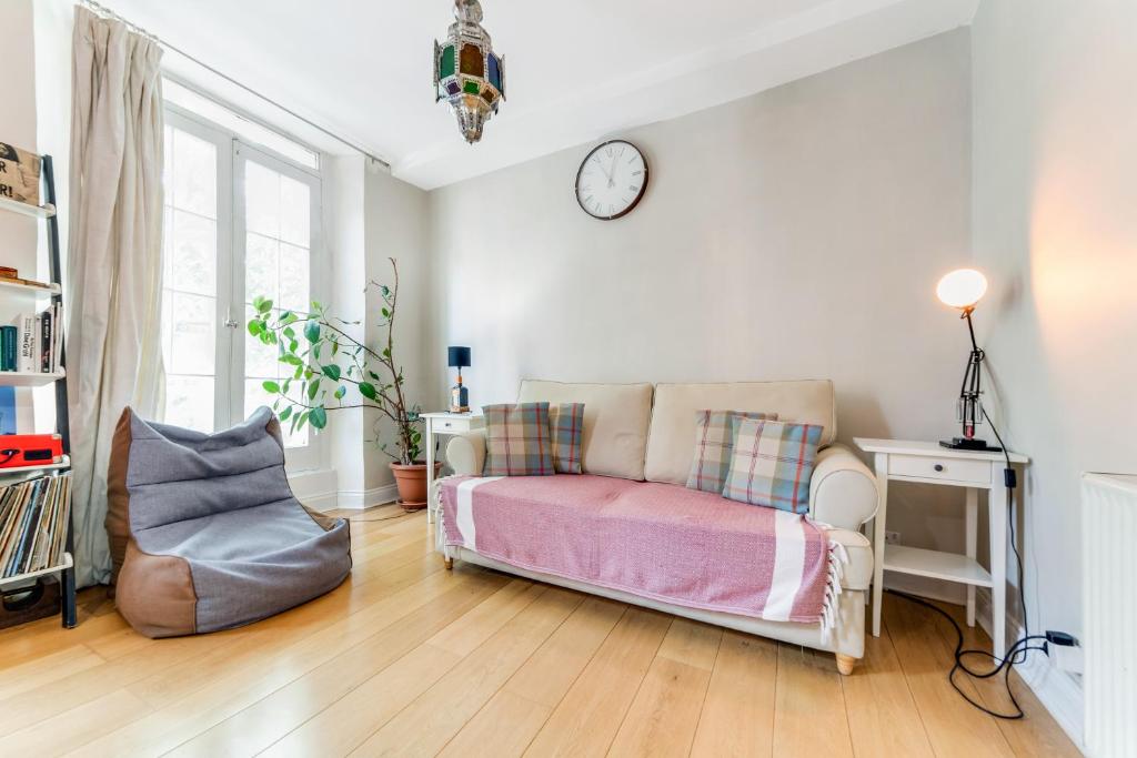 a bedroom with a bed and a clock on the wall at Pass the Keys Sunny Kennington terrace Apartment in London