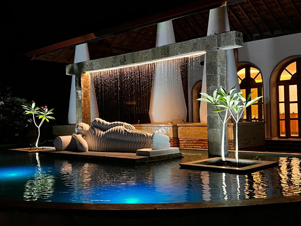 a swimming pool with a sculpture next to a fountain at Avasta Resort and Spa in Anuradhapura