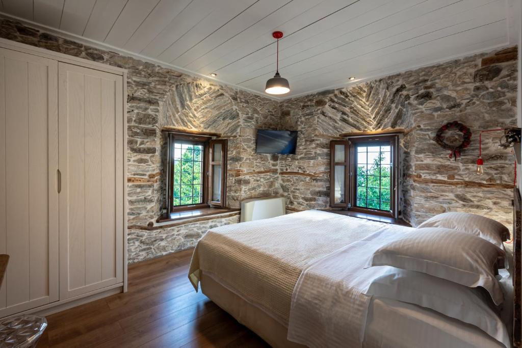 een slaapkamer met stenen muren, een bed en ramen bij Mountain's Secret in Mouresi