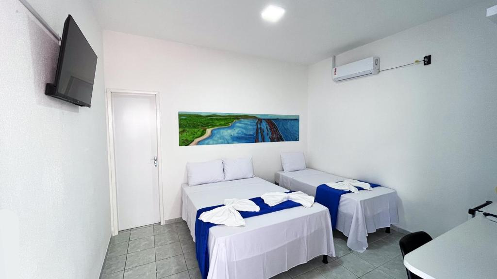 a room with two beds and a flat screen tv at Pousada Estação do Porto in Porto De Galinhas