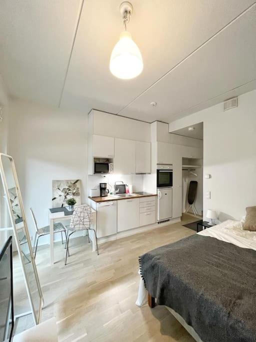 um quarto branco com uma cama e uma cozinha em Kotimaailma - Valoisa ja kompakti yksiö Tikkurilassa em Vantaa