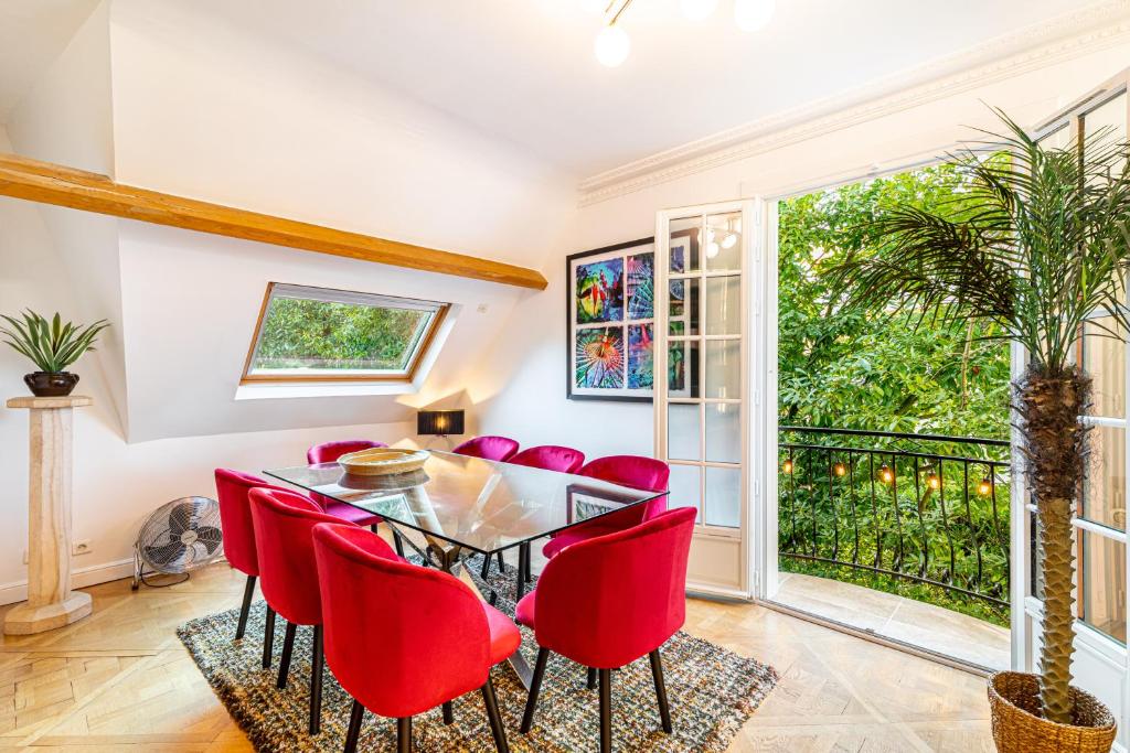 une salle à manger avec une table en verre et des chaises rouges dans l'établissement Stylish Modern Apartement - Art, Design, Garden, Villa des Ammonites, à Meudon