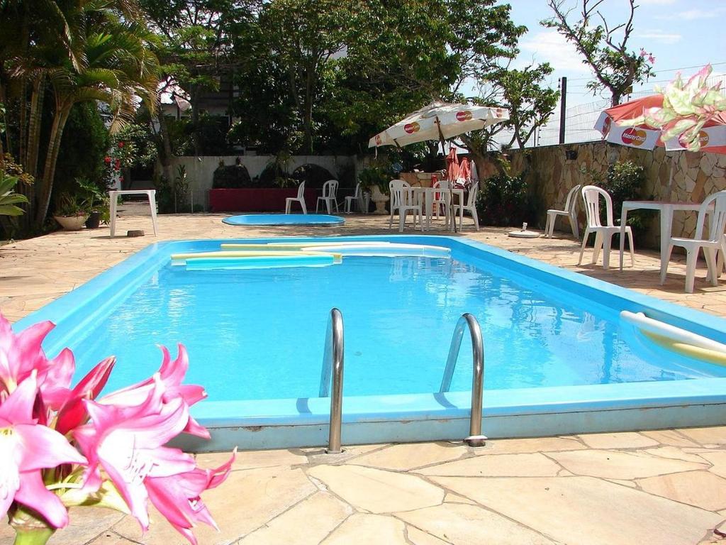 托雷斯的住宿－Pousada Sol e Praia，蓝色的游泳池旁边放着一些粉红色的花朵